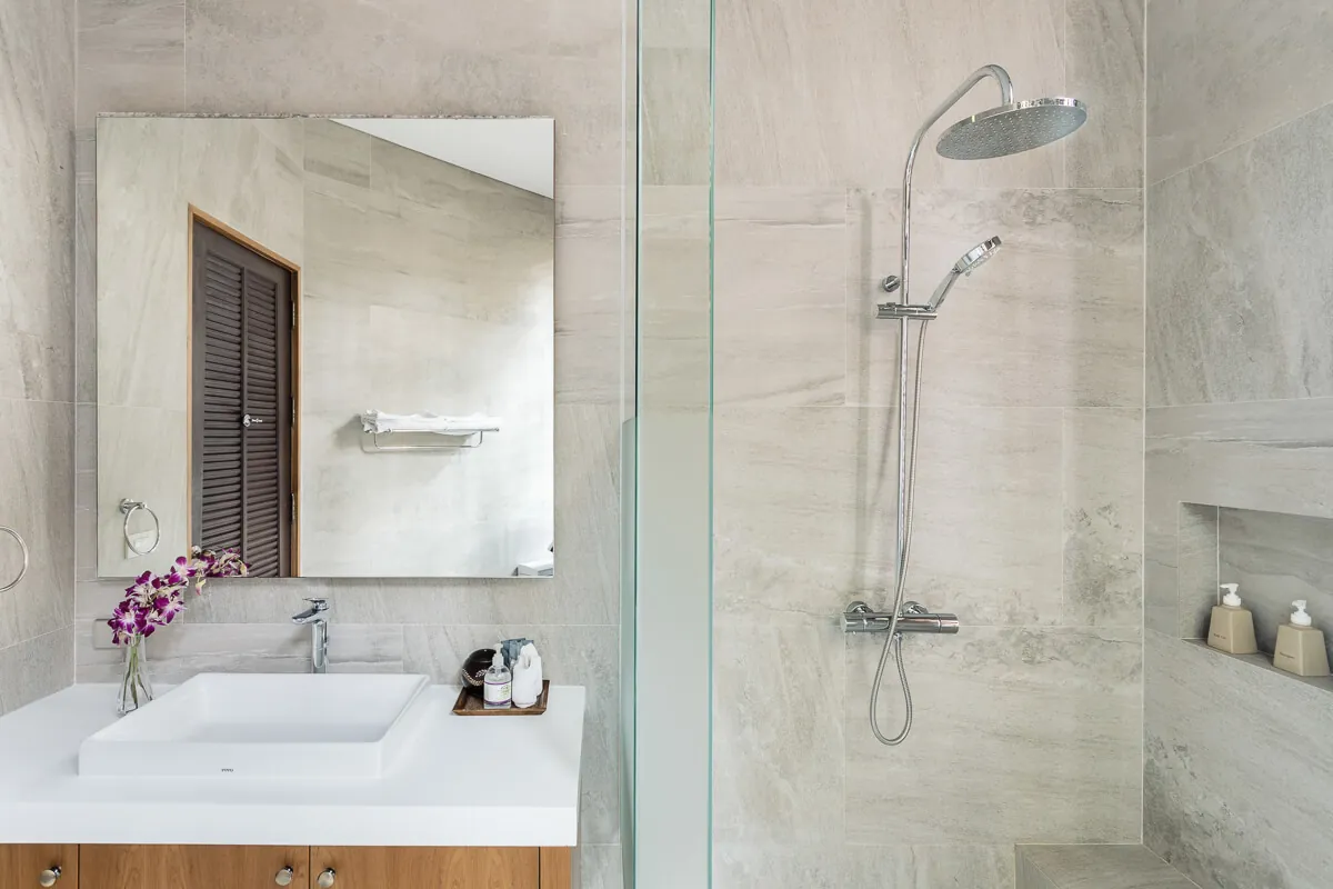 An ensuite vanity and rain shower at Villa Baan Paradise, with an orchid on the bench