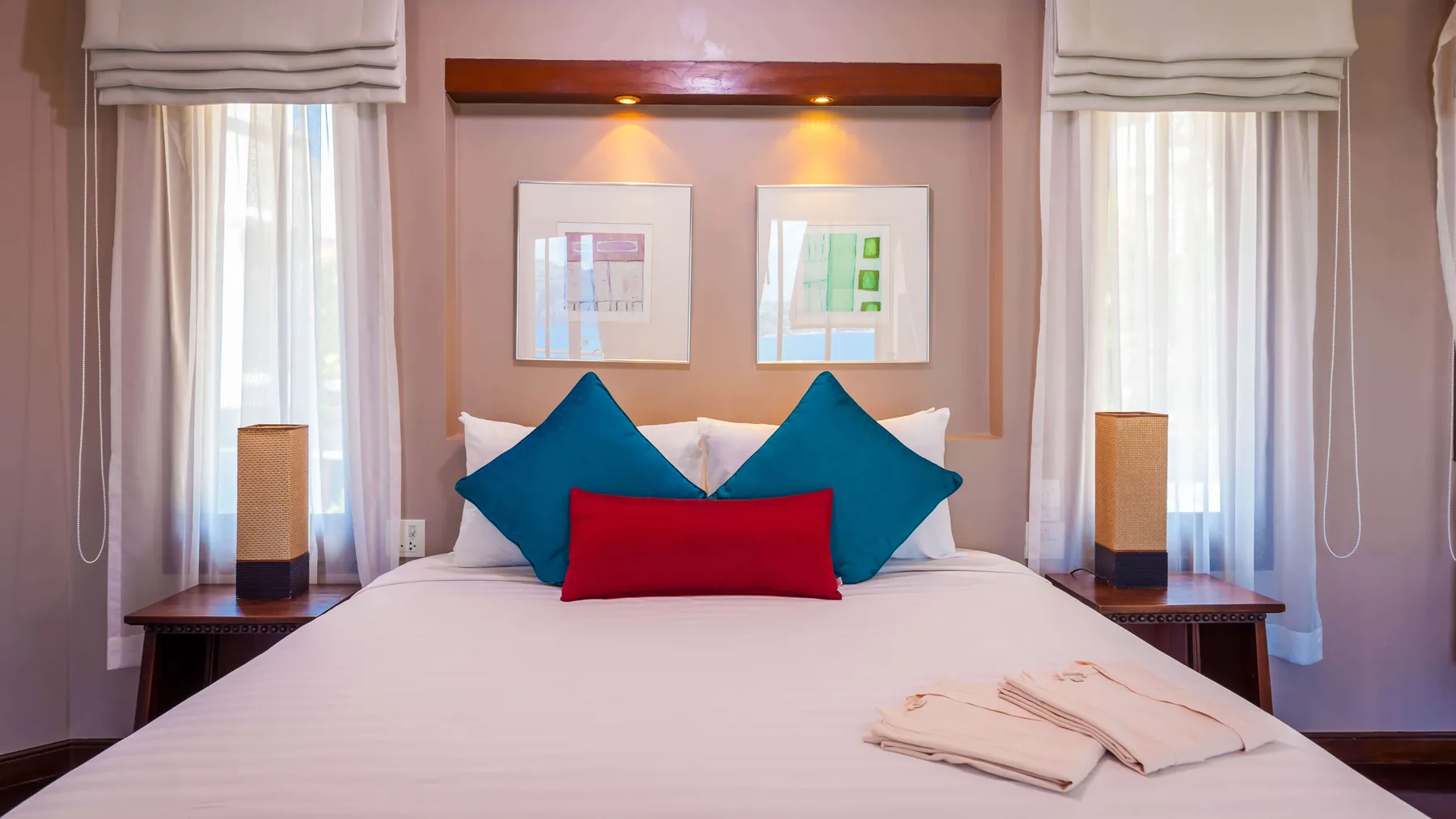 A bedroom at Villa Baan Paradise made up with blue and red cushions and matching bedside lamps