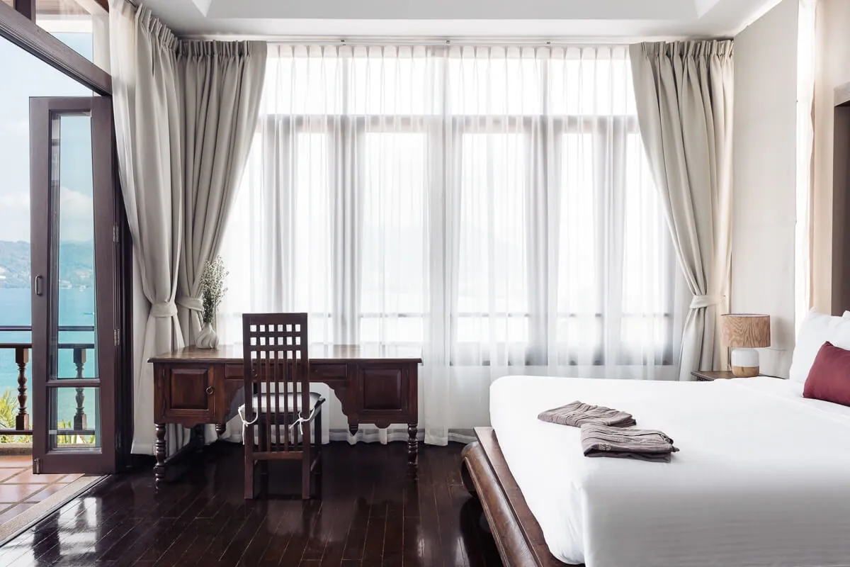 A bedroom with sheer curtains and a door opening onto the bay view