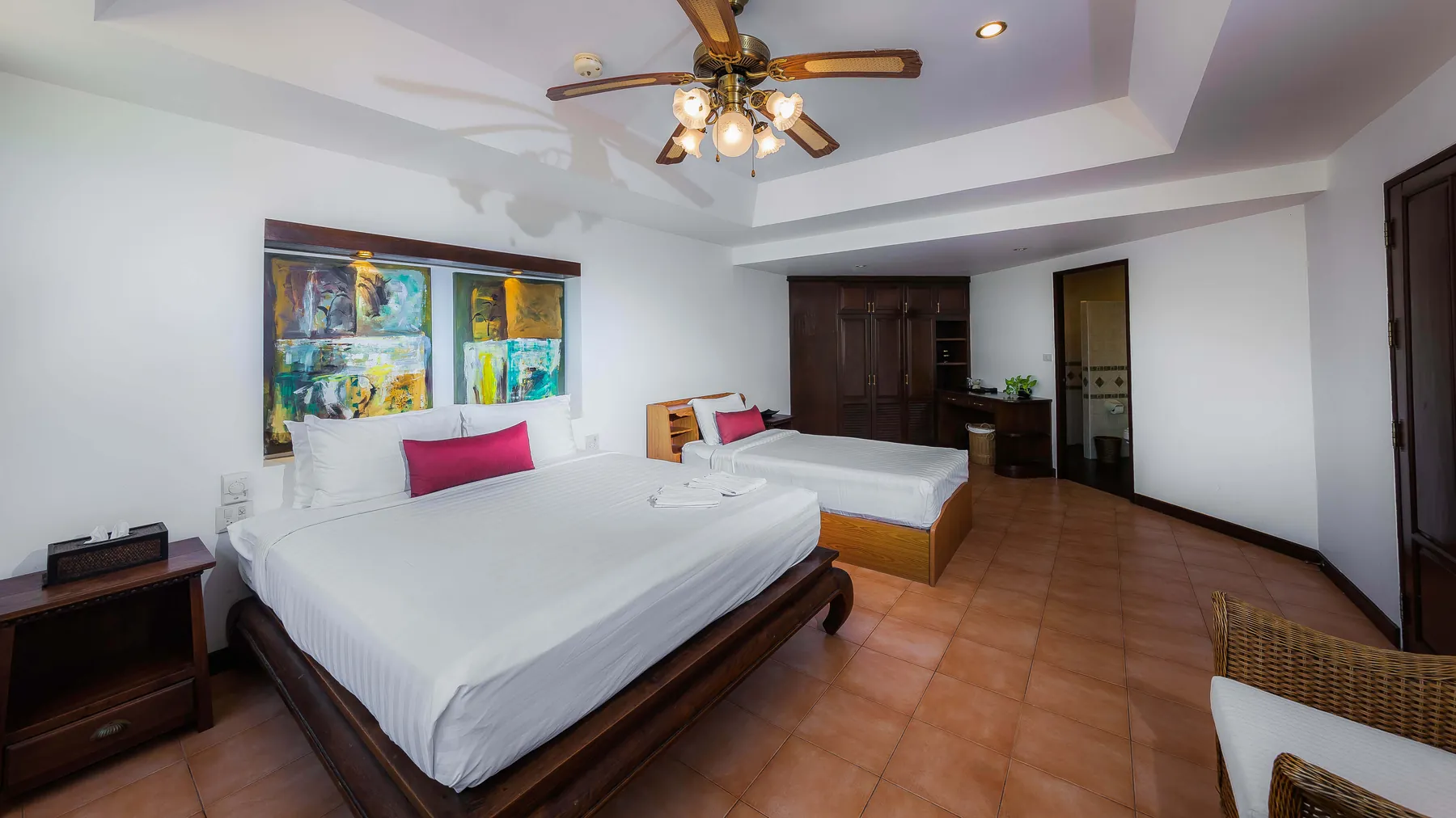 A bedroom at Villa Baan Paradise with a ceiling fan, twin lamps and artwork above the bed
