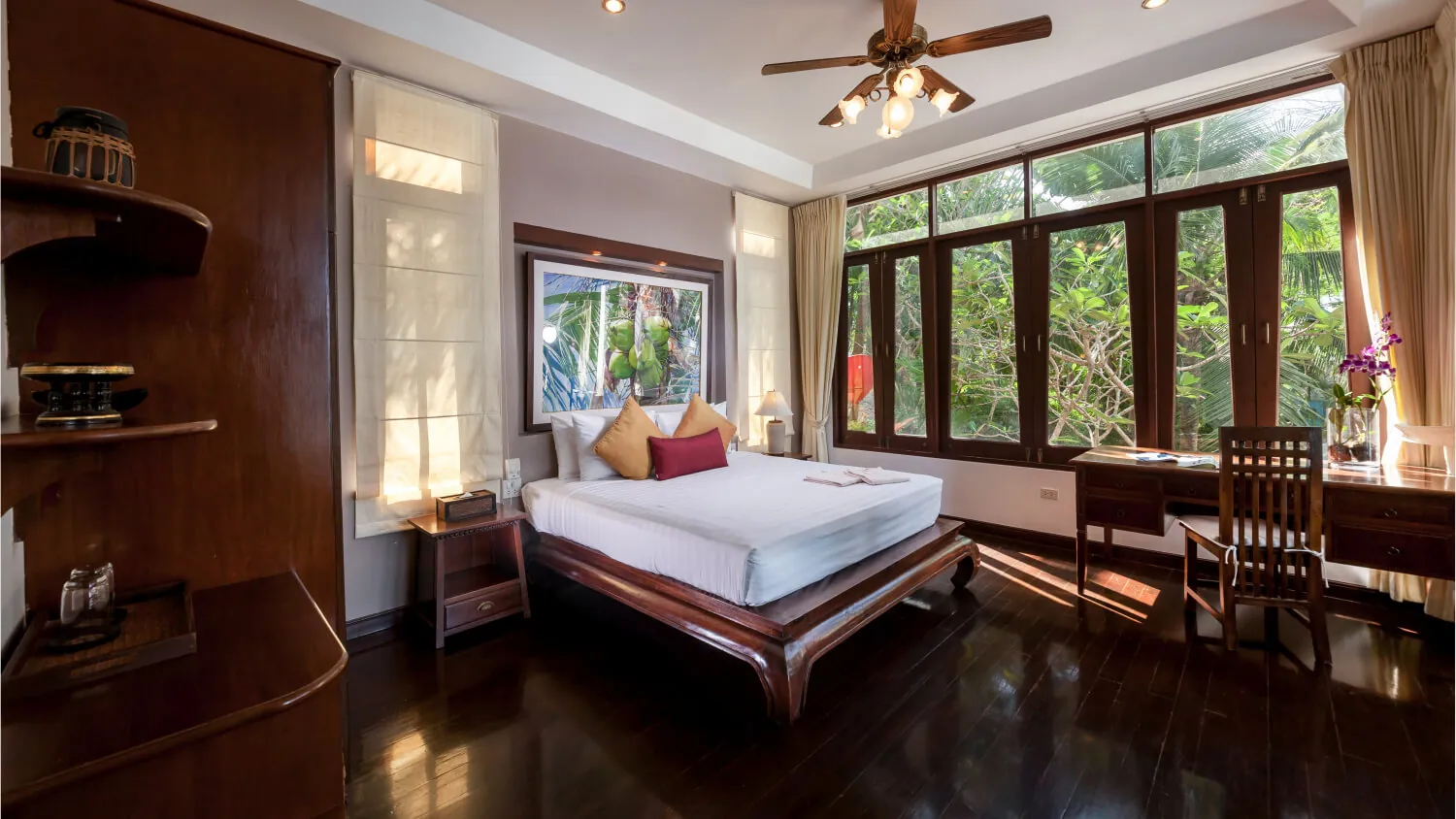A bedroom at Villa Baan Paradise with dark timber joinery, a writing desk and windows on two sides