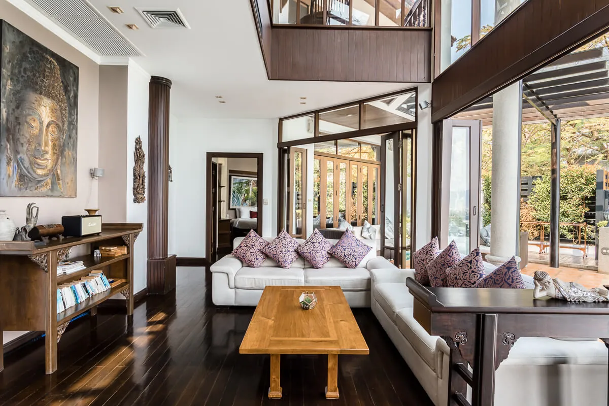 The main living room with its Buddha artwork, white sofas and carved timber coffee table on dark timber floors