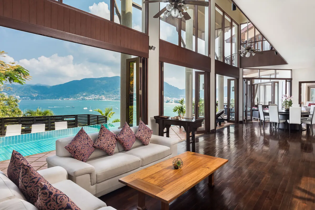 The double-height main living room at Villa Baan Paradise, opening straight onto the pool terrace and the bay