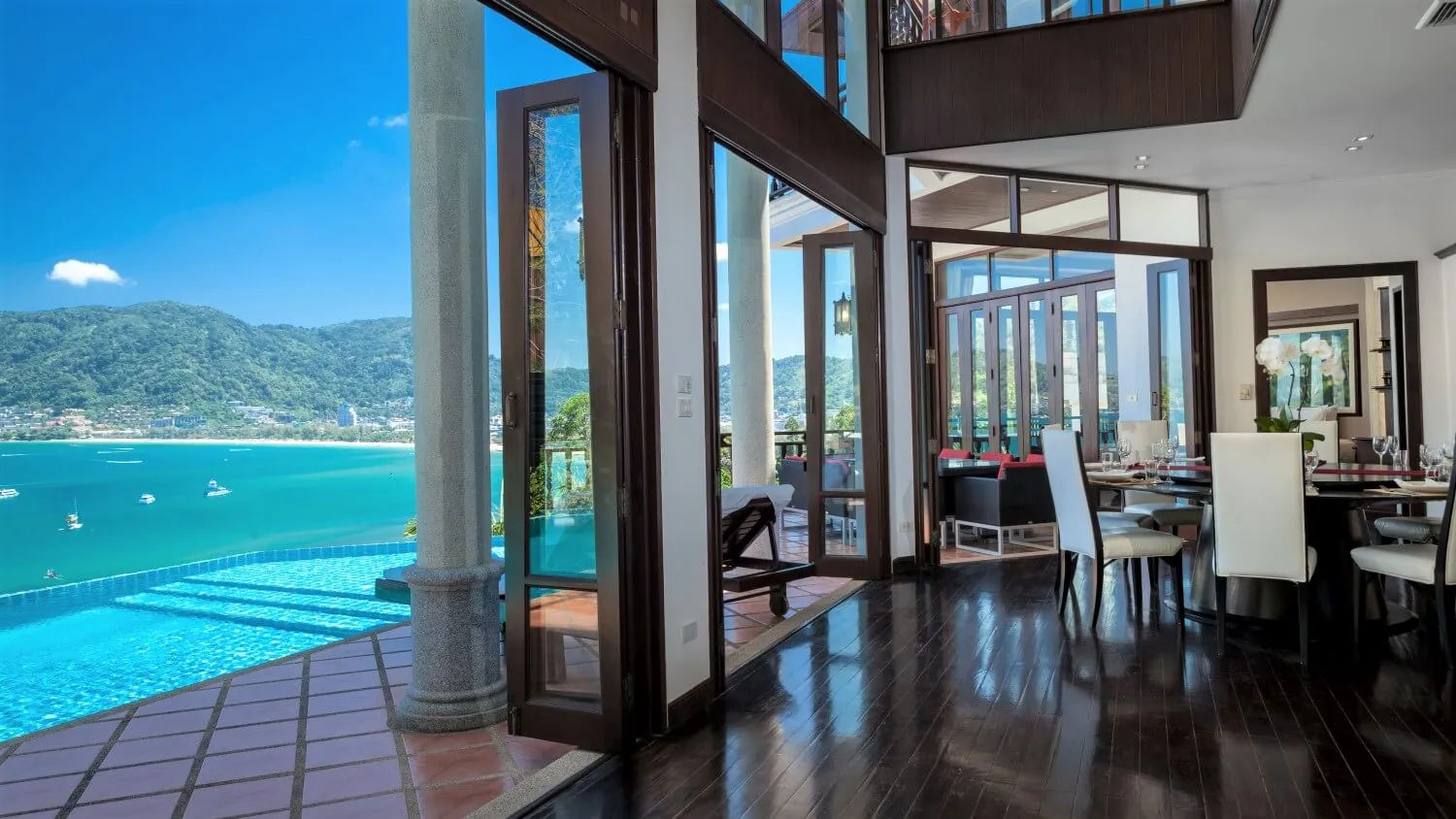 The main living area at Villa Baan Paradise, dark timber floors opening onto the pool and Patong Bay