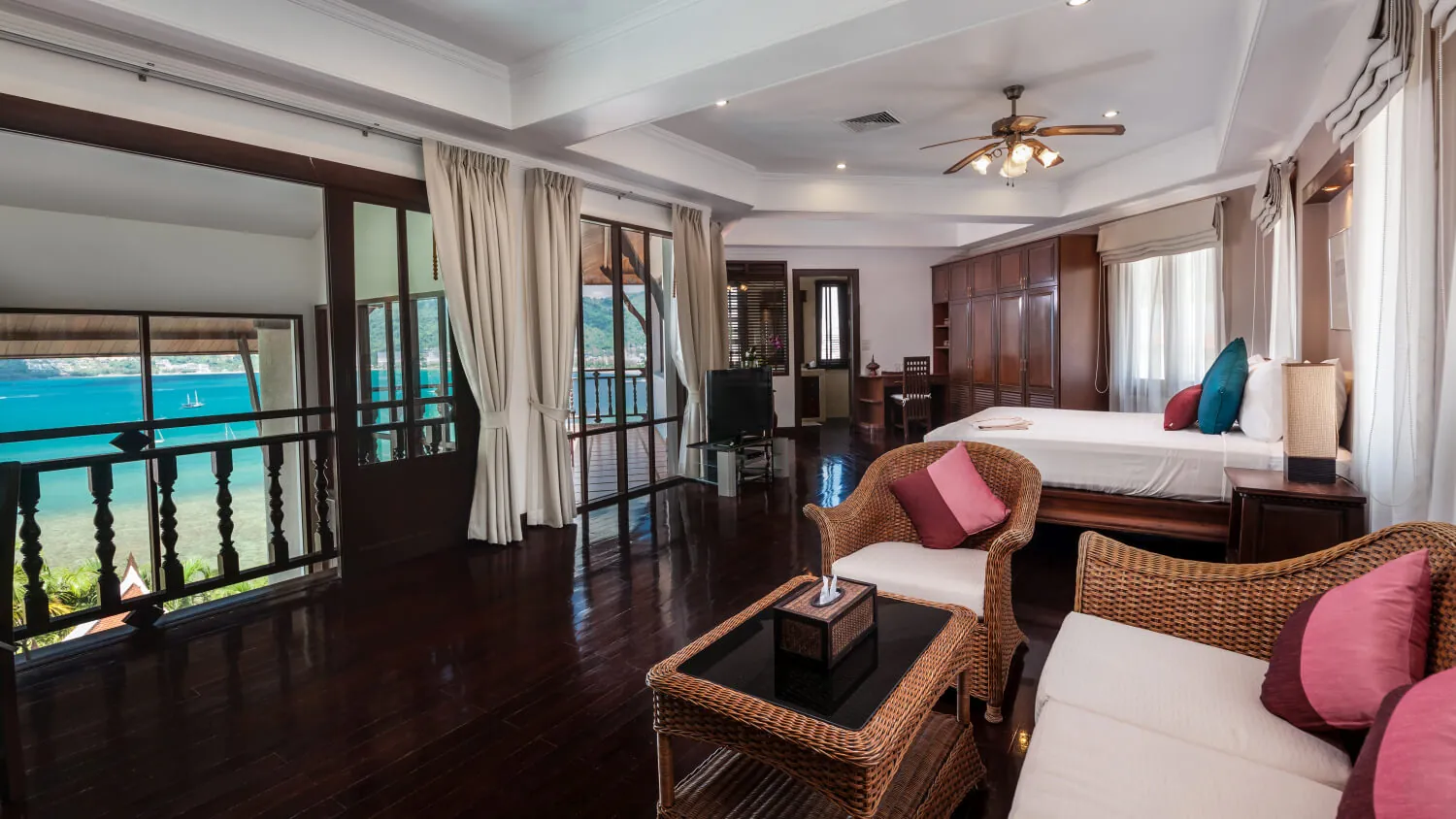 A master bedroom at Villa Baan Paradise with its own sitting area and a balcony over the bay