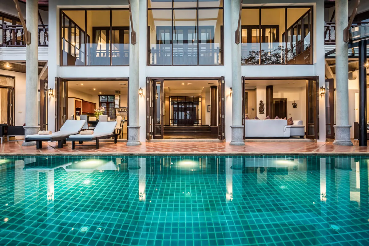 Villa Baan Paradise lit up at dusk, reflected in the still water of the infinity pool