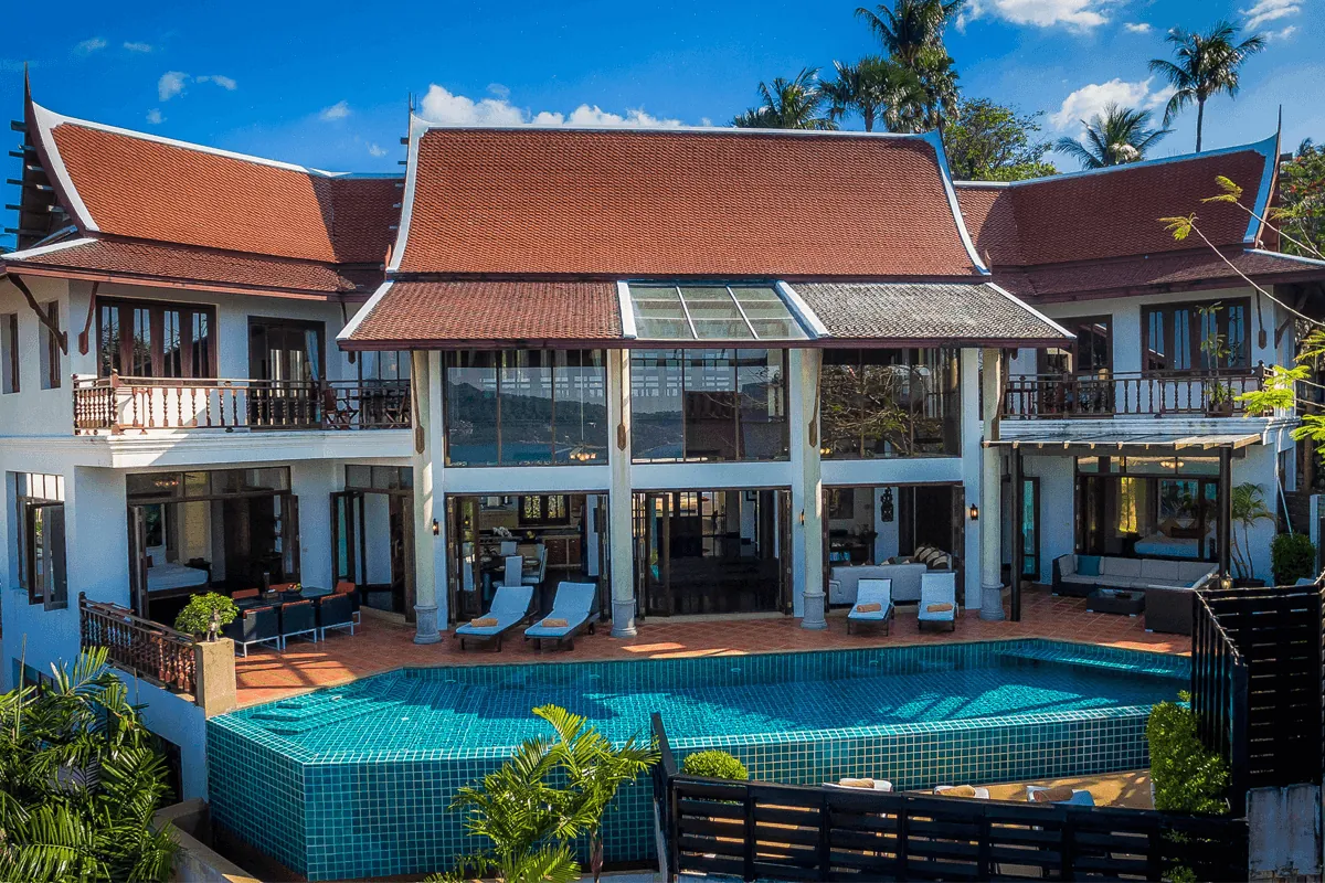 The garden side of Villa Baan Paradise with the pool, loungers and palms in front of the Thai gabled roof